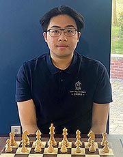 Ralph Tan poses for a photo while sitting in front of a chess board
