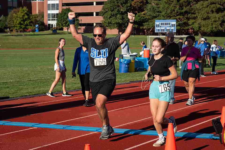 A runner crosses the finish line at the Hustle for Your Health 5K and Fun Run. Photo by Luke Yamnitz.