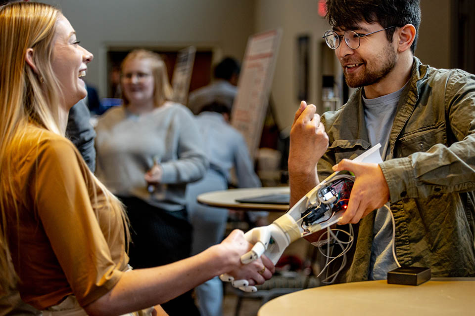 Shakhboz Hasanov, right, demonstrates his team’s project “Myoelectric Prosthesis for Below Elbow Amputation” during the Senior Legacy Symposium on May 2, 2023. Photo by Sarah Conroy. 