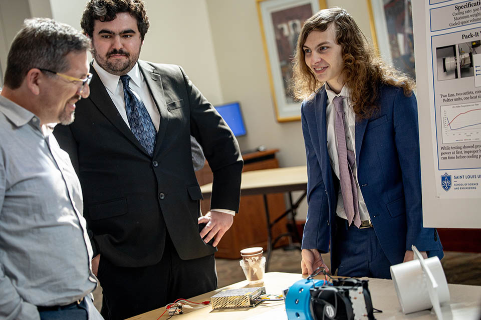 Henry Vance, right, and Zac Tiberghien, center, explain their project “Project Icebox: The Pack-It!” during the Senior Legacy Symposium on May 2, 2023. Photo by Sarah Conroy. 