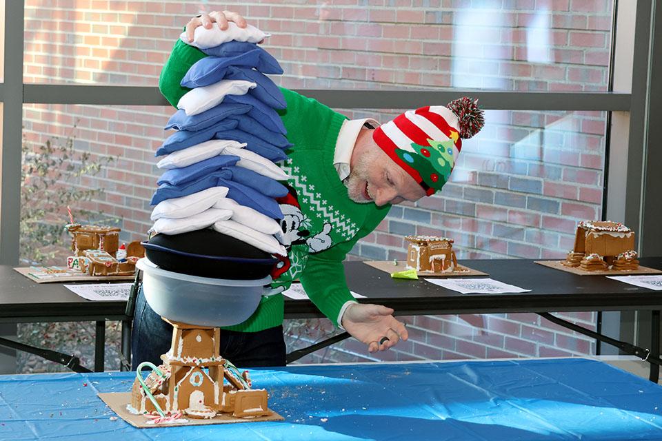 Scott Sell, Ph.D., professor of biomedical engineering and associate dean for undergraduate education in SSE, adds weight to a gingerbread house during the innovation challenge on Friday, Dec. 6. Photo by Joe Barker.