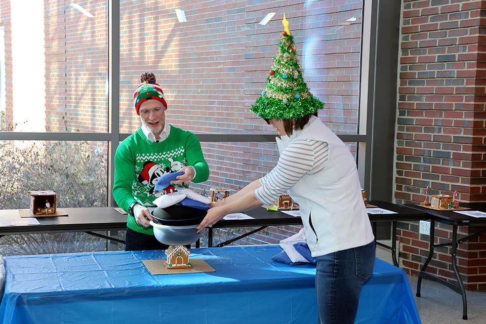 Scott Sell, Ph.D., professor of biomedical engineering and associate dean for undergraduate education in SSE, and Amy Preis, director of undergraduate student success and retention, add weight to a gingerbread house at the Innovation Challenge on Friday, Dec. 6. Photo by Joe Barker. 