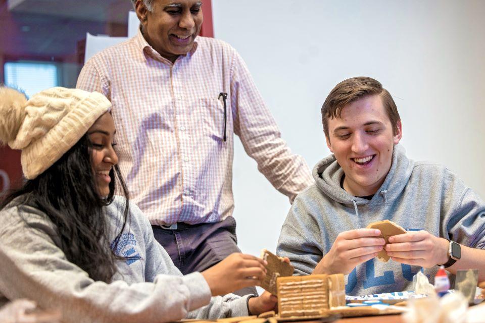 Naveena Mutharasan and Clayton Stout work on their gingerbread house for the SSE Innovation Challenge as Sridhar Condoor, Ph.D., professor of aerospace and mechanical engineering watches on December 2, 2024. Photo by Sarah Conroy.