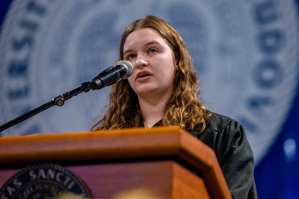 Mary Margaret Bausch, president of Alpha Sigma Nu, introduces the 2024 Nancy McNeir Ring Award winner, Neil Jansen, during the Midyear Commencement on Dec. 14, 2024. Photo by Sarah Conroy. 