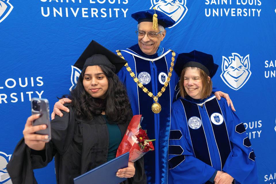 A graduate takes a selfie with President Fred P. Pestello, Ph.D., and Fran Pestello, Ph.D., after Midyear Commencement on Dec. 14, 2024. Photo by Sarah Conroy. 