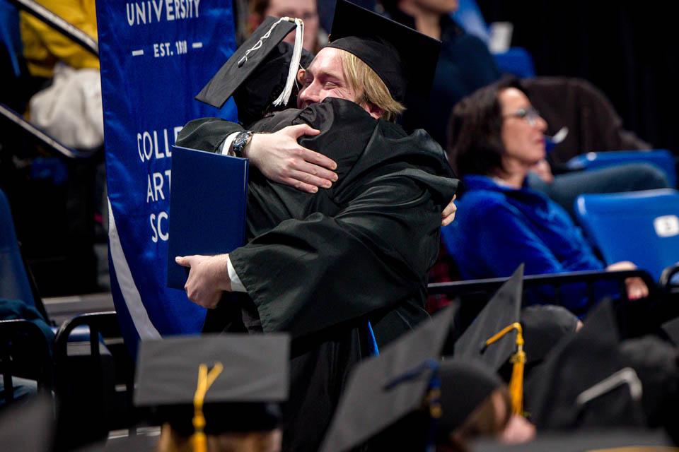 Graduates hug on the way back to their seats during the Midyear Commencement on Saturday, Dec. 14, 2024. Photo by Sarah Conroy. 