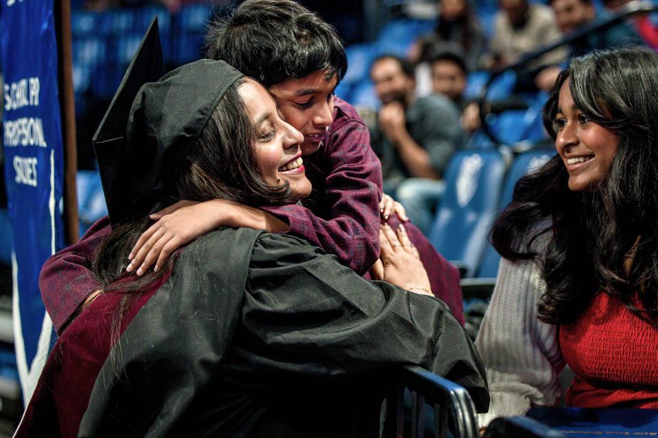 A graduate hugs family in the stands during the Midyear Commencement on Saturday, Dec. 14, 2024. Photo by Sarah Conroy. 