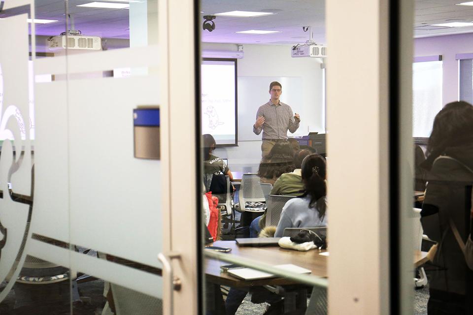 As seen from the outside of the classroom, instructor Sam Biver instructs his class during the first day of the semester.