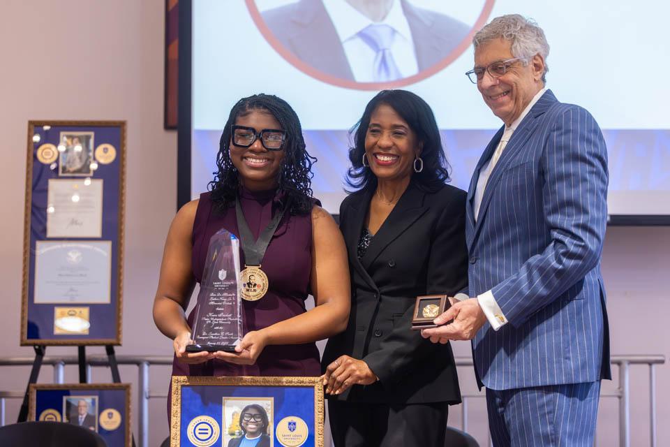 SLU student Kaia S. Prichett, recipient of the Dr. Jonathan C. Smith Emergent Student Leader Award, left, poses with Rochelle D. Smith, vice president of the Division of Diversity and Innovative Community Engagement and President Fred P. Pestello, Ph.D., during the Martin Luther King Jr. Memorial Tribute on Jan. 23, 2025. Photo by Sarah Conroy. 