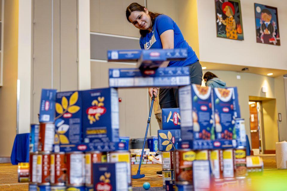 Members of the SLU community play miniature golf on a course constructed from shelf-stable grocery items at Golf and Give, an SSE Innovation Challenge to benefit Billiken Bounty on February 25, 2025. Photo by Sarah Conroy.