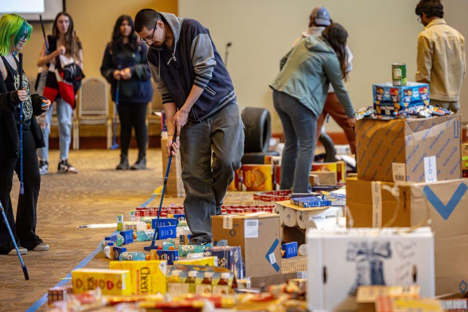 Members of the SLU community play miniature golf on a course constructed from shelf-stable grocery items at Golf and Give, an SSE Innovation Challenge to benefit Billiken Bounty on February 25, 2025. Photo by Sarah Conroy.