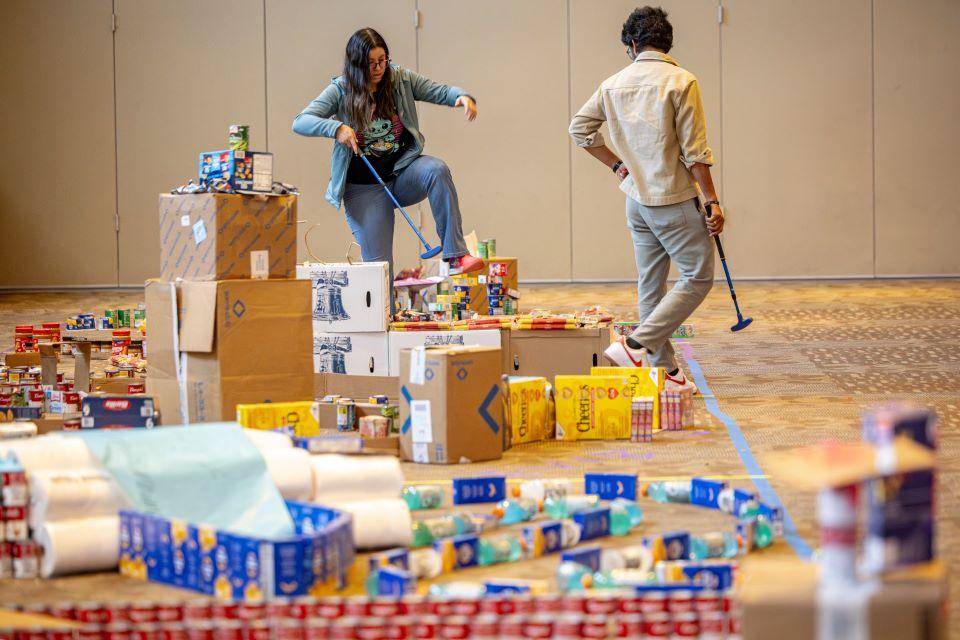 Members of the SLU community play miniature golf on a course constructed from shelf-stable grocery items at Golf and Give, an SSE Innovation Challenge to benefit Billiken Bounty on February 25, 2025. Photo by Sarah Conroy.