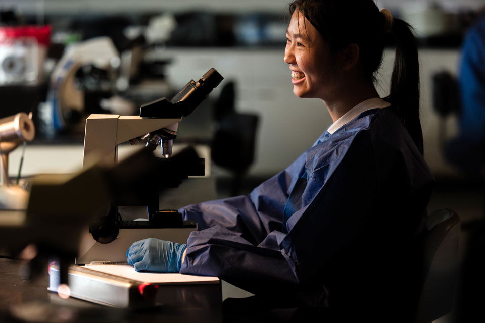 Student smiling in front of them while doing research