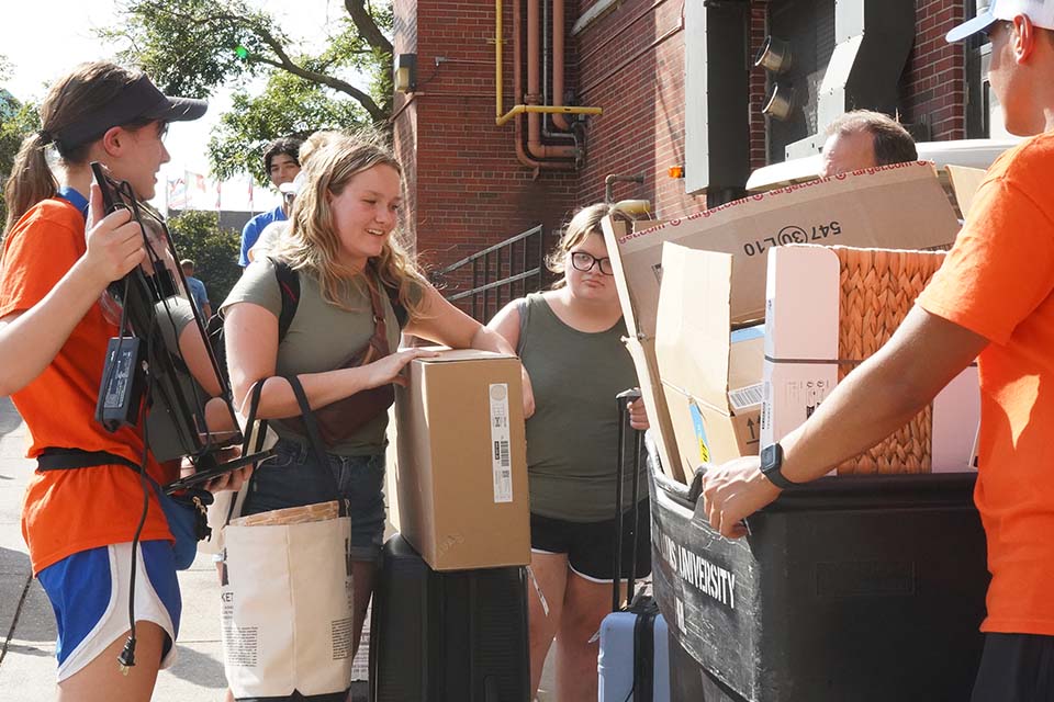 Legacy Billiken Students help a first-year student carry things to a residence hall.