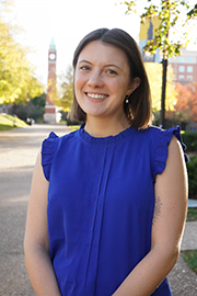 Headshot photo of Jackie Barnes with a clocktower and trees in the background.