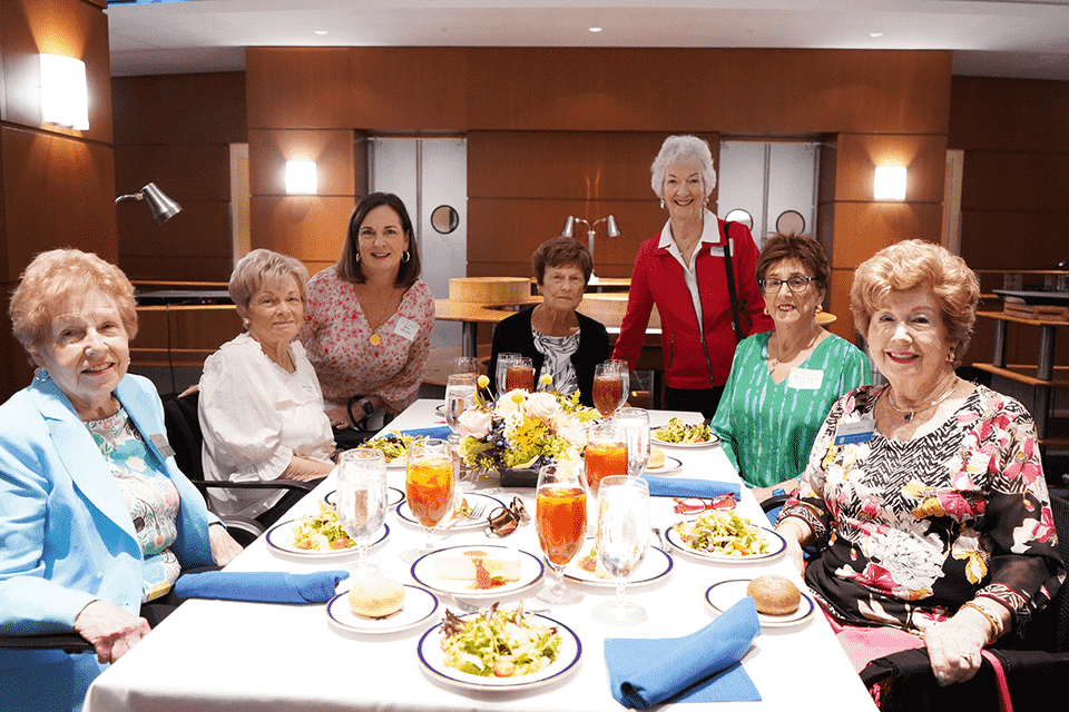A group of women pose for a photo together at a table during the spring luncheon.