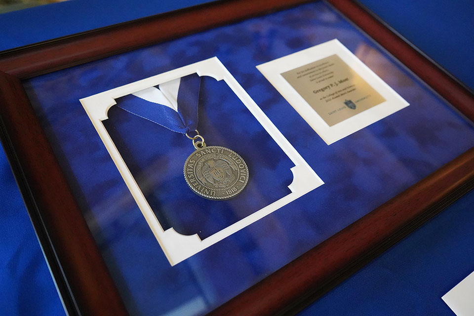 Alumni Merit Award A medal inside a frame on a table.