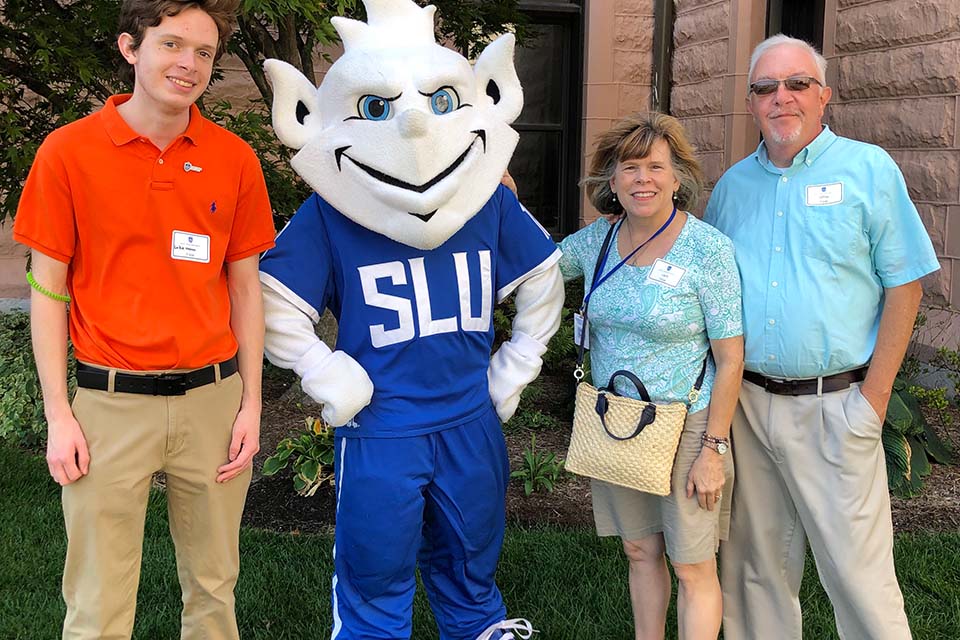 Three members of the Fister family pose for a photo with the Billiken.