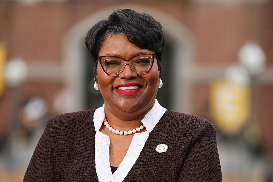 LaTonia Collins Smith A woman poses for a photo on a campus outside a brick building.