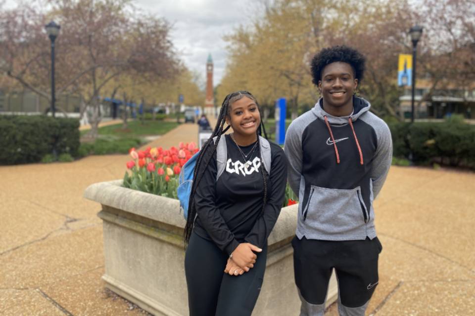 Two high school students pose for a photo on West Pine Mall, with the clock tower in the background.