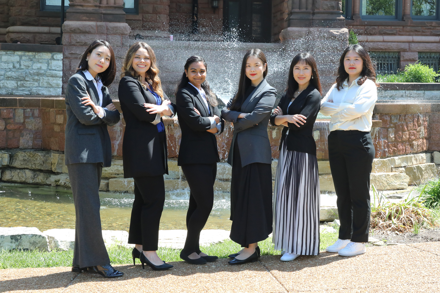 2024-25 Chaifetz School of Business PhD Students pose in front of a fountain while wearing business attire.
