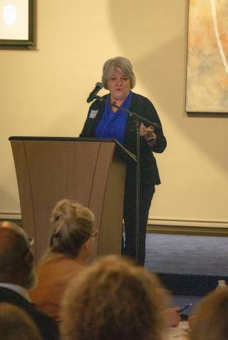 Merlene Gilb, Ed.D., Assistant Professor, School of Education stands at a lectern to talk to attendees.