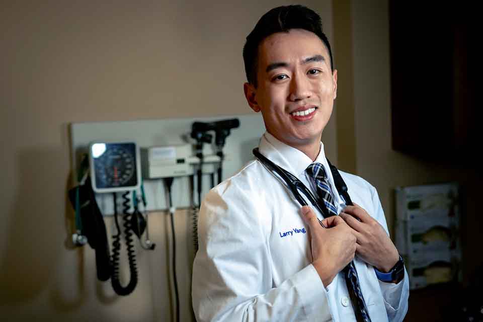 Larry Yang poses with a lab coat and stethoscope