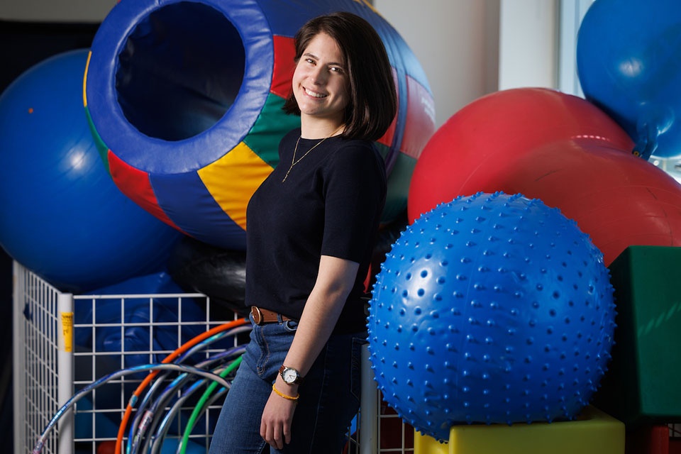 A student stands next to a collection of large inflatable balls, hula hoops and other items used in therapy.