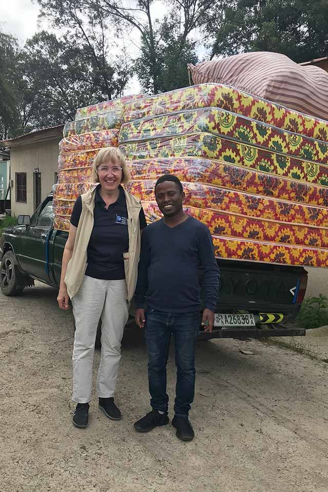 Karen Vilcinskas poses for a photo with a man in front of a pick up truck full of mattresses.