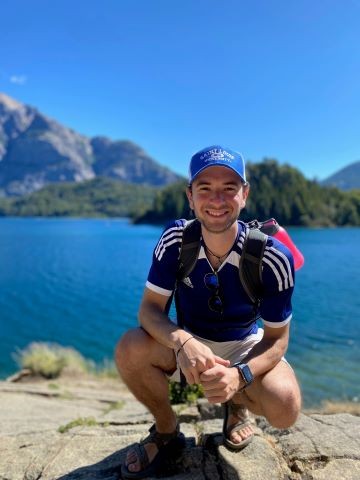 Joseph Richard outside on a rock near a body of water on a clear day