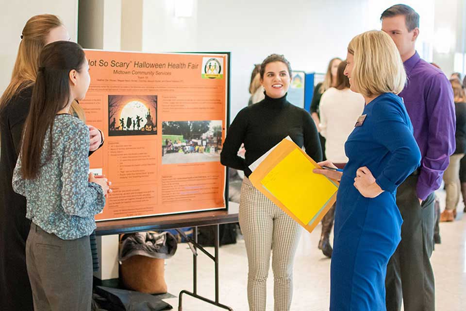 A group of college students presents a posterboard with student research findings