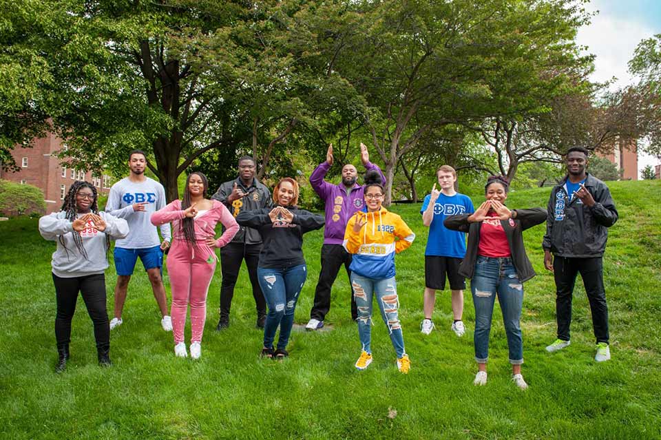 Members of SLU's NPHC community pose outdoors while wearing their organization's letters.