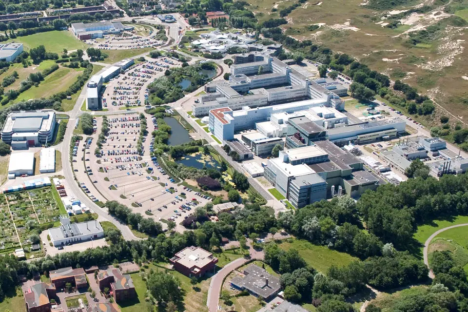 Aerial shot of a complex of multiple office buildings and a large parking lot.
