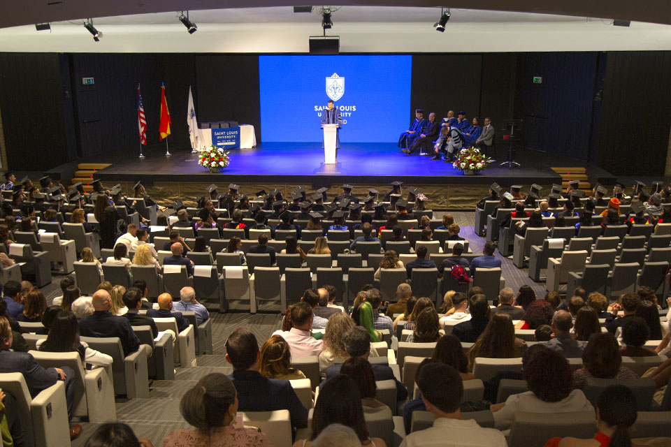 Commencement Ceremony May 2023 Graduates and audience members are shown from the back, watching a speaker on stage during the commencement ceremony of May 2023.