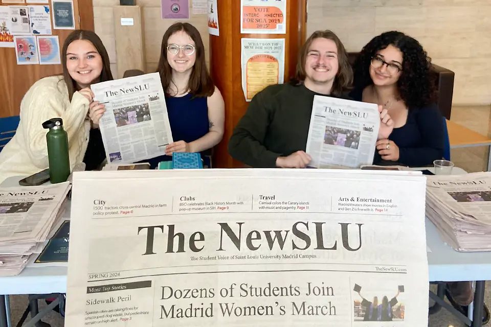 The NewSLU staff members pose with print edition Newspaper held up to camera with four students smiling and holding up newspapers.