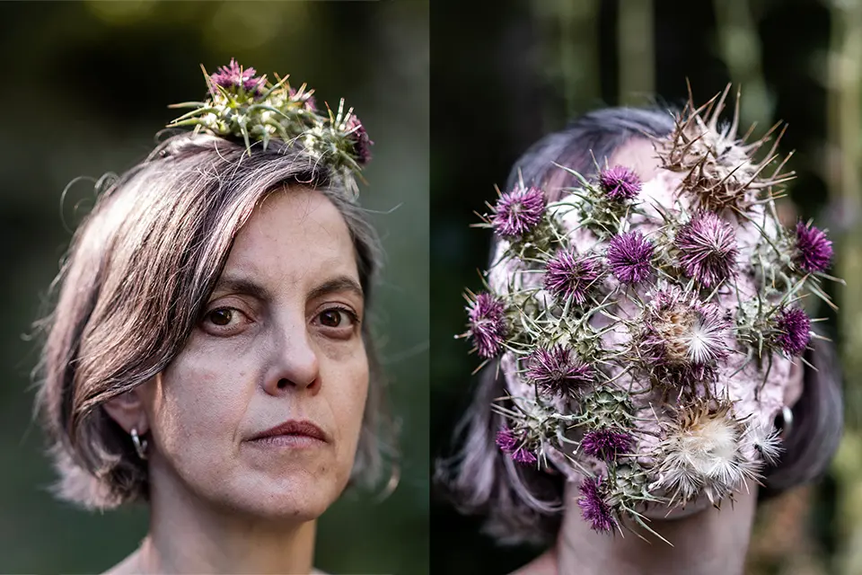 Woman covering her face with dried thistles next to self portrait. 