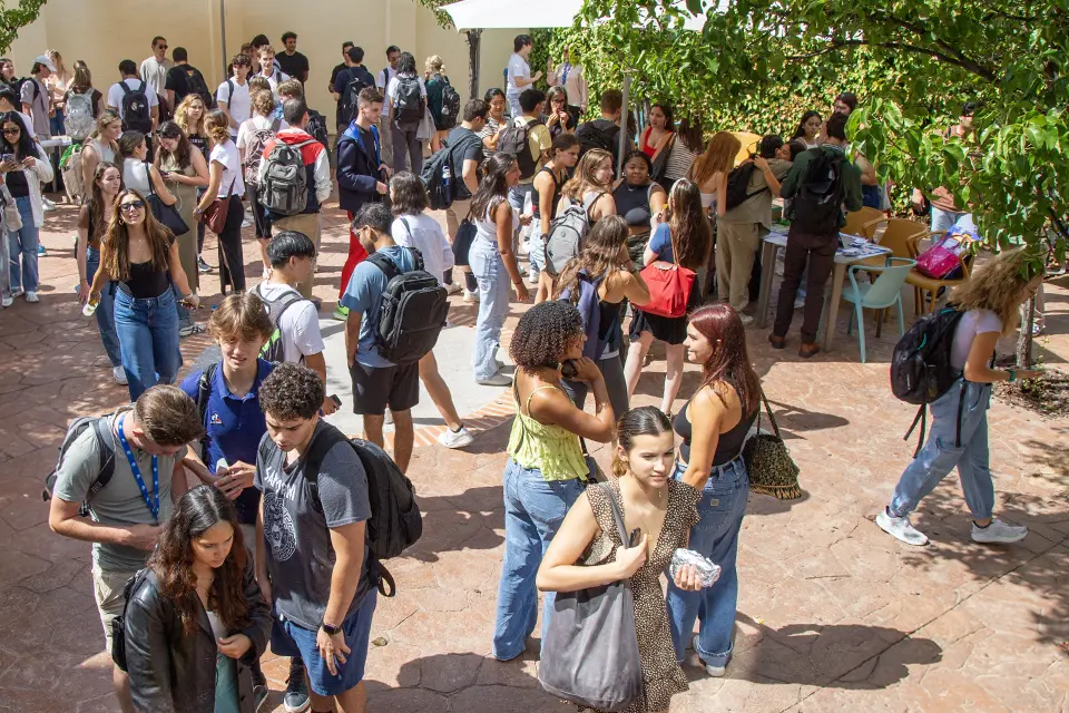 Students gather in groups around patio.