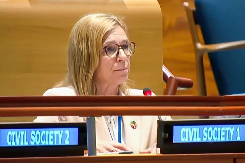 Woman smiles at camera in front of meeting space at the UN's headquarters.