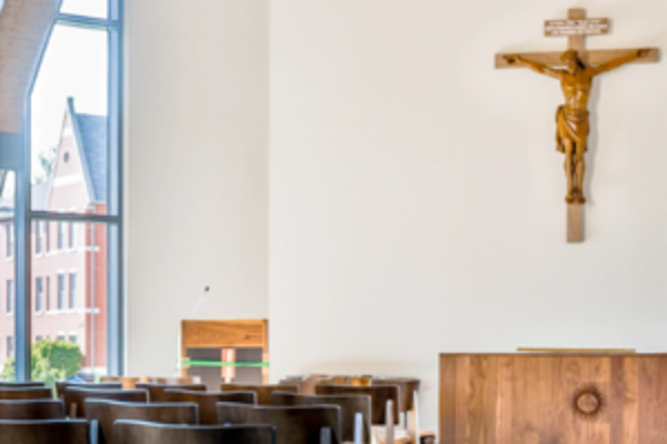 View of a chapel with seats, and altar and crucifix.