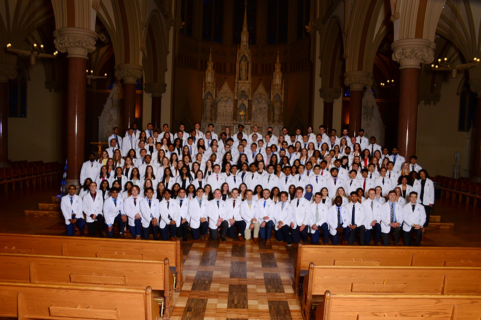 A group of first-year medical students pose for a photo inside a church.