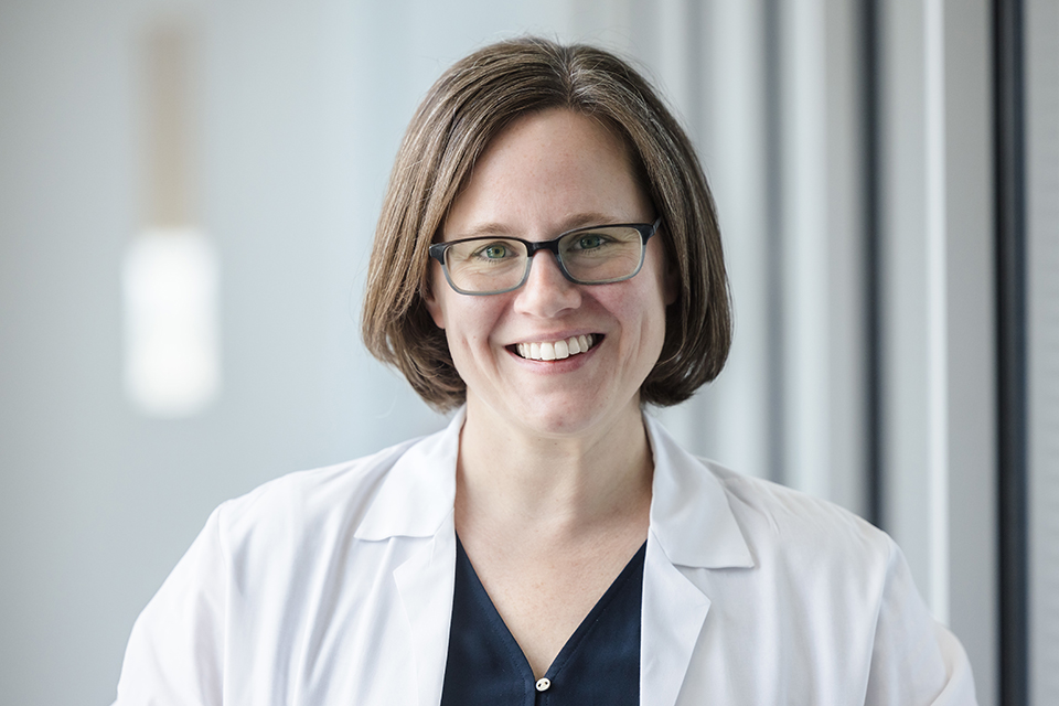 SLU researcher Elise Alspach, Ph.D., poses in her white lab coat for a photo.