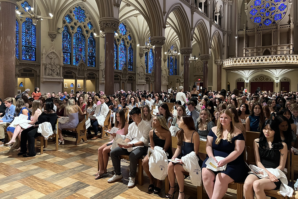 A group of people gather inside a church to celebrate the SLU School of Nursing White Coat Ceremony.