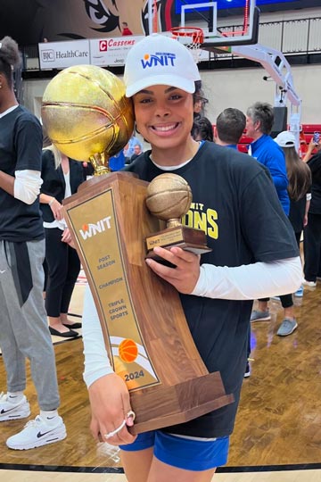 Peyton poses for a photo with her trophies after winning the WNIT.