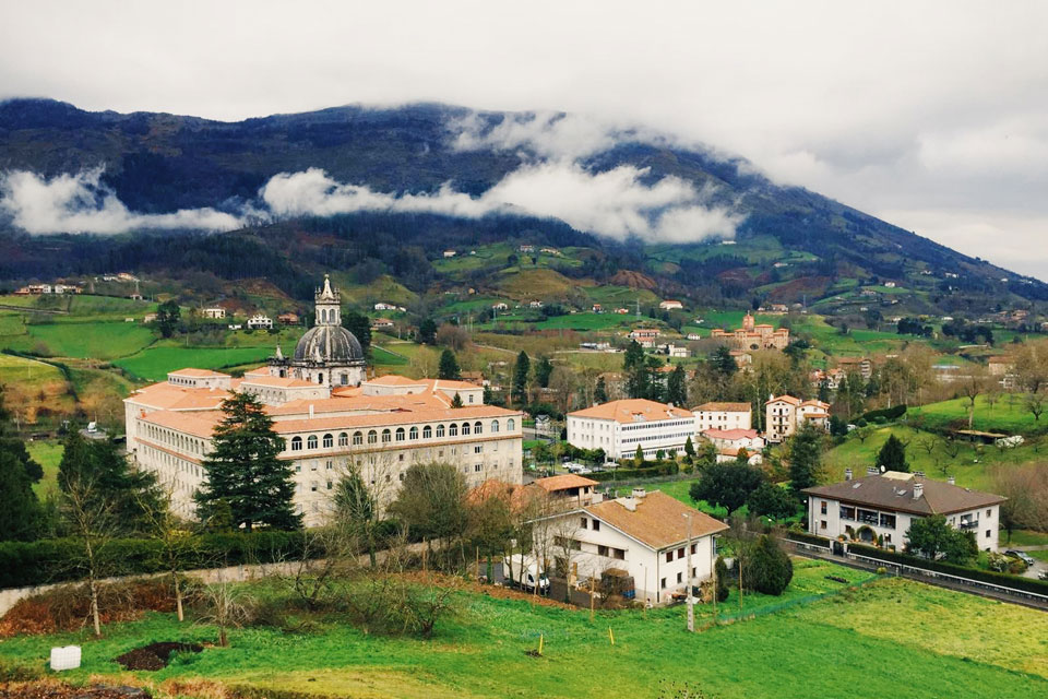 A site in Spain's Basque Country including towers and a view over a town on a clear day with green hills in the background.