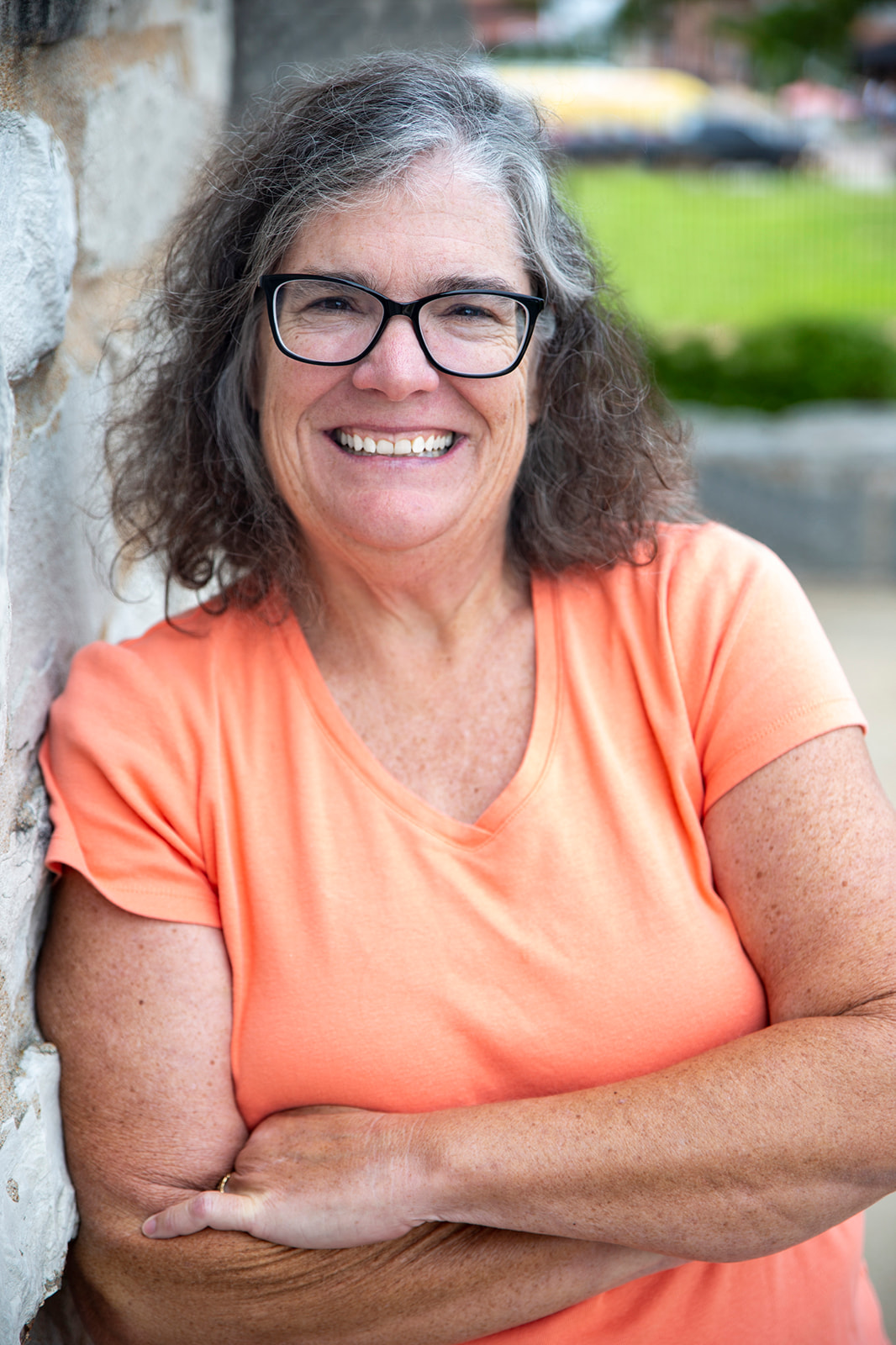 Dyan McGuire leans up against a wall and smiles for a head shot.