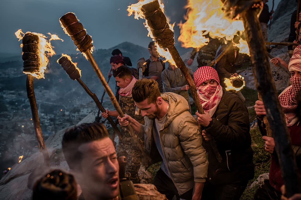 Young men carry wooden torches down a mountain during Kurdish Newroz celebrations in Akre, Kurdistan, Iraq.