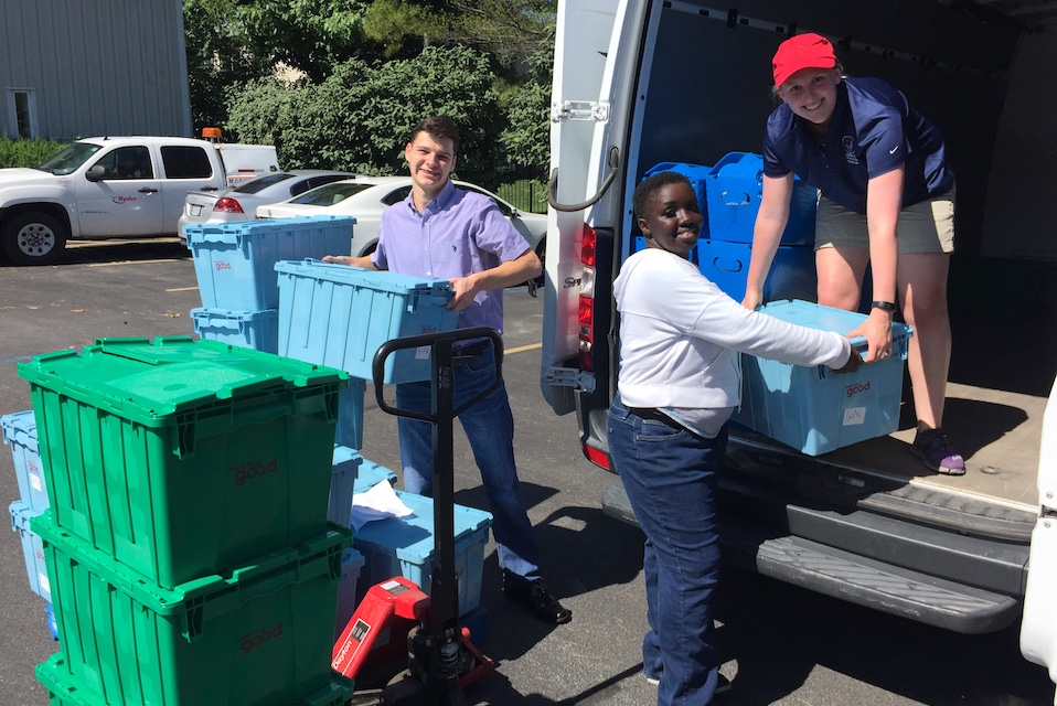 Volunteers unload crates of food from a van