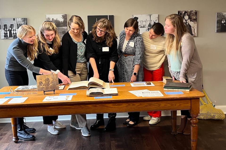 Group photo of SCAC researchers examining texts and other materials on a table.