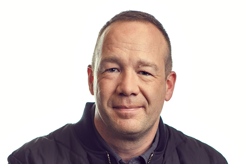 A headshot of SLU alumnus Tim Bantle, a middle-aged white man with close-cropped hair and wearing a dark jacket