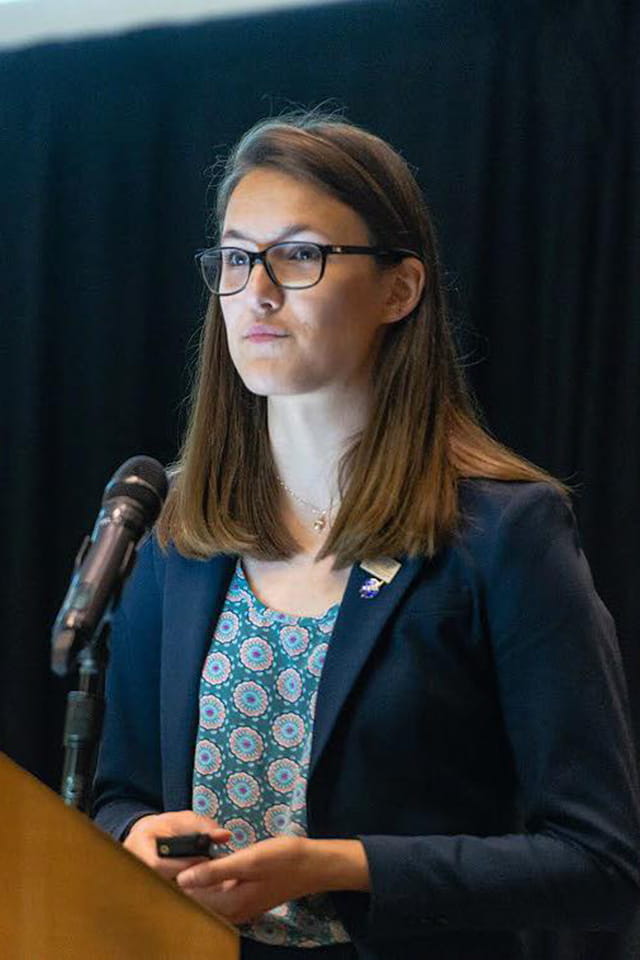 Portrait of Lindsey Jasper speaking in front of a microphone